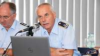 Zwei Soldaten vor einem Mikro und neben einem aufgestellten Laptop. Einer spricht.
