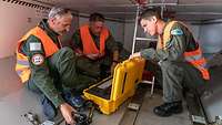 Personen im Laderaum eines Flugzeugs schauen auf technisches Gerät