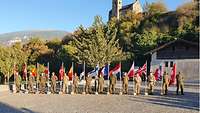 Die internationalen Delegationen stehen mit einer Landesflagge auf dem Platz vor dem Château de Valère in Sion