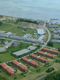 Mehrer rötliche Gebäude sind entlang eines Weges angeordnet.