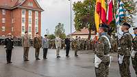 Sieben Generale stehen nebeneinander vor einer Flaggenabordnung.