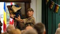 Ein britischer Soldat hält einen goldenen Stiefel auf einer Holzplakette hoch.
