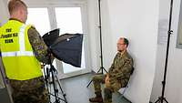 Ein Soldat sitzt auf einem Hocker und wird von einem anderen Soldaten fotografiert
