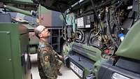 Ein Soldat schaut auf den Motor eines LKW