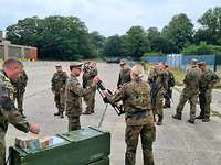 Eine Soldatin übergibt einem Soldaten ein Gewehr