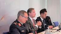 Ein General sitzt mit mehreren Personen am Tisch.