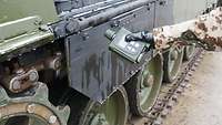 Ausschnitt eines Kampfpanzers davor ehält ein uniformierter Arm einen Geigerzähler