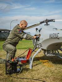 Ein Soldat kniet vor einer Drohne vom Typ Sea Falcon und überprüft die Technik.