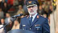 Ein Brigadegeneral ist hinter einem Rednerpult mit Mikrofon während einer Rede zu sehen.