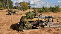 Deutsche Soldaten stehen in Schützenlöchern mit ihren Gewehren in Stellung und zielen