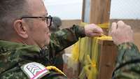 Ein Soldat bindet ein gelbes Band an das Kreuz