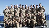 Mehrere Soldatinnen und Soldaten stehen und hocken für ein Gruppenbild an Deck