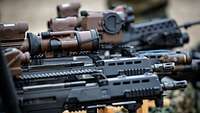 Blick über mehrere schwarze und braune Waffen, die aufgestellt sind.