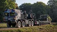 Ein Schwerlasttransporter mit Tieflader wird mit einem Militärfahrzeug beladen.