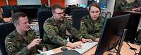 Drei Soldatinnen und Soldaten arbeiten gemeinsam an zwei Computern