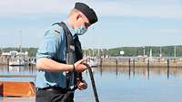 Ein Marinesoldate hält ein dickes Seil in der Hand.