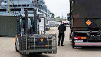 Ein Gabelstaplerfahrer transportiert Metallkisten mit Munition in einem Hafen.