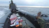 Ein Schlauchboot fährt auf dem Meer und hat Cola-Dosen geladen.