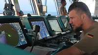 Der Navigationsmeister Ein Soldat sitzt vor einer Bildschirmkonsole. Er betrachtet ein Radarbild, auf dem Schiffe als Punkte dargestellt sind.