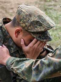 Beistand leisten Ein Soldat sitzt auf dem Boden und verdeckt sein Gesicht mit seinen Händen. Ein weiterer Soldat leistet ihm Beistand.