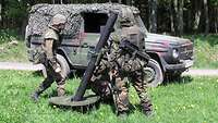 Soldaten bringen einen Mörser in Stellung, im Hintergrund ein Geländewagen.