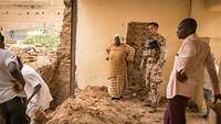 Soldaten und Zivilisten stehen in einem offenen Raum mit einer Baustelle