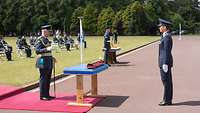 Übergabe des International Sword of Honour Prinz Charles und Nicole Nordholz stehen einander gegenüber, das Schwert liegt auf einem Tisch vor dem Prinzen.