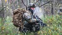 Ein Soldat kniet im Wald.