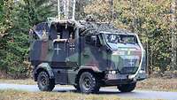 Ein auf einem Armeeauto aufgesessener MG-Schütze sichert eine Straße.