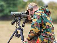 Der Spotter unterstützt bei der Zielerfassung Ein sitzender Soldat schaut durch ein Spektiv.