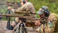 Soldaten sucht den Druckpunkt des deutschen G22 Im Vordergrund schaut ein Soldat durch das Zielfernrohr, während im Hintergrund unscharf ein weiterer Soldat zu erkennen ist.
