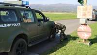 Ein Soldat kontrolliert die Reifen an einem Militärfahrzeug auf Steine bevor er auf das Flugfeld fährt