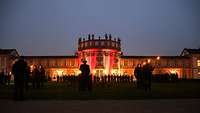 Vor dem nächtlich beleuchteten Schloss Biebrich befinden sich für ein Gelöbnis angetretene Soldatinnen und Soldatinnen.