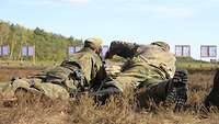 Zwei Soldaten liegen auf dem Rasen und justieren ein Gewehr G36.