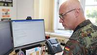 Ein Soldat sitzt vor an seinem Schreibtisch vor zwei Monitoren