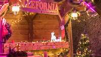 Ein mit Lichterketten und künstlichen Tannengestecken weihnachtlich dekorierter Betreuungsstand aus Holz
