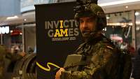 Ein Soldat des in Ausrüstung vor einem Werbeplakat der Invictus Games