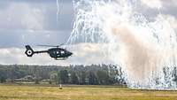 Ein Hubschrauber der Bundeswehr über einer Wiese verbirgt sich hinter einer Nebelwand