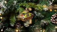 Ein kleiner Panzer als Christbaumschmuck am Tannenzweig.