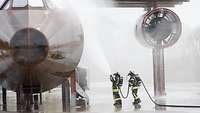 Two firemen extinguish the mock-up of a transport aircraft