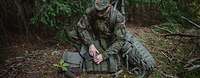 Persönliche Ausrüstung und Bekleidung Ein Soldat kniet mit seiner Ausrüstung im Wald.