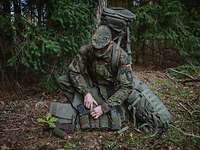 Persönliche Ausrüstung und Bekleidung Ein Soldat kniet mit seiner Ausrüstung im Wald.