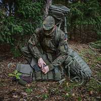Ein Soldat kniet mit seiner Ausrüstung im Wald.