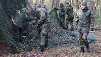 Mehrere Soldaten spannen ein Tarnnetz.