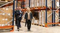 Die Verteidigungsministerin und vier weitere Personen stehen in einem großen Lagerraum und unterhalten sich.