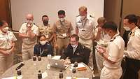 Mehrere Soldaten blicken auf einen Computerbildschirm und besprechen sich untereinander.