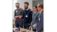 Gute Stimmung im Team 4 Seminarteilnehmende stehen an einem Tisch vor einem Lego Serious Bauwerk