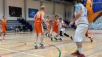 Ein Spieler dribbelt mit Kontakt zu seinem Gegenspieler zum Korb, weitere versuchen ihn den Weg zu blockieren. 