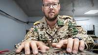 Im Serverraum sitzt ein Soldat an einem PC und schreibt auf einer Tastatur