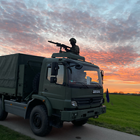 Bundeswehrfahrzeug in der Abenddämmerung. Ein Soldat mit Maschinengewehr ragt aus der Dachluke.